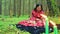 A young gypsy woman lights candles in a circle in the forest.