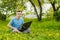 Young gyu freelincer at work on a laptop on a green grass and trees background