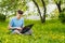 Young gyu freelincer at work on a laptop on a green grass and trees background
