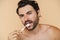 Young half-naked man looking at camera while brushing his teeth