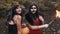 Young halloween girl friends in black and red witch dress having fun in the forest park with traditional autumn holiday