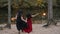 Young halloween girl friends in black and red witch dress having fun in the forest park with traditional autumn holiday