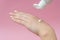 Young hands squeezing cream from tube on pink background. For beauty or medicine products