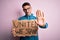 Young handsome activist man asking for union holding banner with united stand message with open hand doing stop sign with serious