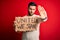 Young handsome activist man protesting holding cardboard with unity message with open hand doing stop sign with serious and