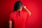 Young handsome african american afro man with dreadlocks wearing red casual t-shirt Posing backwards pointing ahead with finger