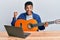 Young handsome african american man learning classical guitar from online tutorial screaming proud, celebrating victory and