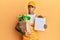 Young handsome african american man wearing courier uniform with groceries from supermarket and clipboard clueless and confused