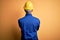 Young handsome african american worker man wearing blue uniform and security helmet standing backwards looking away with crossed