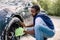 Young handsome African guy holding green sponge, washing car wheel with foam. Cleaning of modern rims of luxury blue