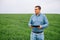 Young handsome agronomist, agriculture engineer standing in green wheat field with tablet in hands in early summer. Agribusiness