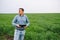 Young handsome agronomist, agriculture engineer standing in green wheat field with tablet in hands in early summer. Agribusiness