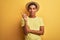 Young handsome arab man wearing t-shirt and summer hat over isolated yelllow background with a big smile on face, pointing with