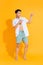 Young handsome Asian man in casual summer outfit pointing two hands aside on colorful yellow background