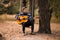 Young handsome attractive man in sweater playing guitar in forest sitting on swing. Casual man, life style.