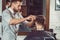 Young handsome barber making haircut of attractive man in barbershop