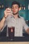 Young handsome barman pouring cocktail into glass