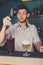 Young handsome barman pouring cocktail into glass