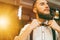 Young handsome bearded barber straightens his bow-tie. Copy space