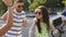 Young handsome bearded guy funny greets two pretty fashionable girls outdoors