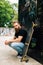 Young handsome bearded man with beard sitting with longboard on the street