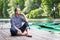 Young handsome bearded man sitting on wooden pier, relaxing and thinking