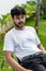 A young handsome bearded man wearing a blank white shirt doing a pose outdoor