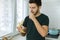 A young handsome brunette man is standing in the kitchen