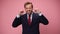 young handsome business man wearing suit and tie on pink background