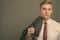 Young handsome businessman with blond hair against gray background