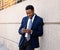 Young handsome businessman using mobile phone app sending message outside office in urban city