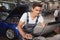 Young handsome car mechanic repairing vehicle in his garage