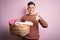 Young handsome caucasian man doing housework chores holding laundry wicker basket happy with big smile doing ok sign, thumb up