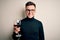 Young handsome caucasian man drinking an alcoholic glass of red wine over isolated background with a happy face standing and