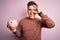 Young handsome caucasian man holding piggy bank for savings over pink background with happy face smiling doing ok sign with hand