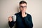 Young handsome caucasian man wearing glasses drinking a cup of hot coffee cover mouth with hand shocked with shame for mistake,