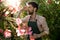 Young handsome cheerful gardener covering nose from smell with fingers.