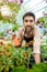 Young handsome cheerful gardener smiling, watering, taking care of flowers.