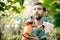 Young handsome cheerful gardener smiling, watering, taking care of flowers.