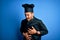 Young handsome chef man with beard wearing cooker uniform and hat over blue background with hand on stomach because nausea,