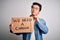 Young handsome chinese activist man protesting asking for change holding poster serious face thinking about question, very