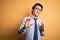 Young handsome chinese businessman wearing glasses and tie over yellow background disgusted expression, displeased and fearful