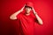 Young handsome chinese delivery man wearing cap standing over isolated red background suffering from headache desperate and
