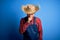 Young handsome chinese farmer man wearing apron and straw hat over blue background feeling unwell and coughing as symptom for cold