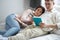 A young handsome clever man is reading a book to his wife ,