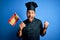 Young handsome cooker man with beard wearing uniform holding spain spanish flag screaming proud and celebrating victory and