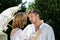 Young handsome couple dressed in vintage costume. Woman is holding parasol as she leans in to kiss her lover