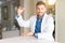 Young handsome doctor man at the clinic gesturing with hands showing big and large size sign, measure symbol