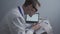 Young handsome doctor man in glasses and white lab coat examines results of electrocardiographic examination of patient