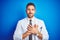 Young handsome doctor man wearing white professional coat over isolated background smiling with hands on chest with closed eyes